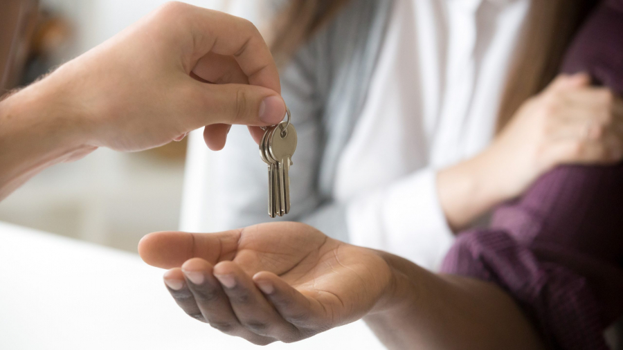 Realtor giving african customer keys, couple buying new house, closeup